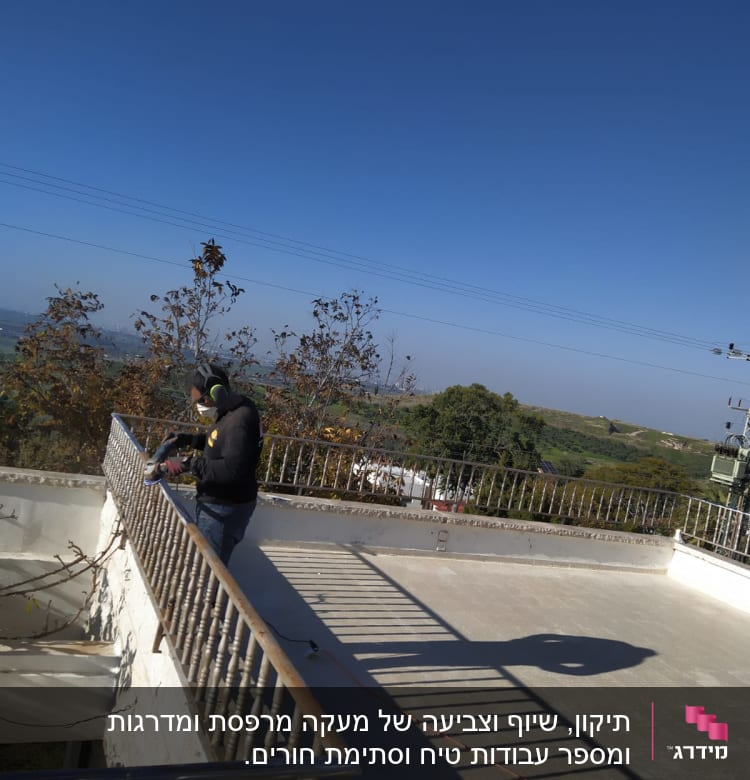 אדם משייף מעקה מתכת על גג פתוח